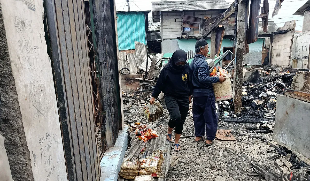 Pedagang Pasar Pejuang Pratama mengais sisa dagangan yang masih bisa diselamatkan usai kios mereka ludes terbakar, Sabtu malam, 23 Agustus 2025. (Sumber: POSKOTA | Foto: Nurpini Aulia Rapika)