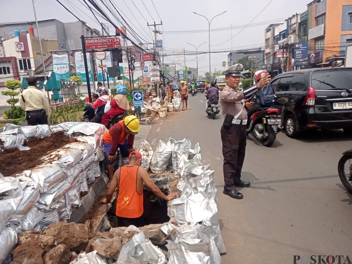Petugas kepolisian mengatur lalu lintas di Jalan Kartini, Depok, saat proyek galian kabel menyebabkan kemacetan dan menyempitkan ruas jalan. (Sumber: Poskota/Angga Pahlevi)