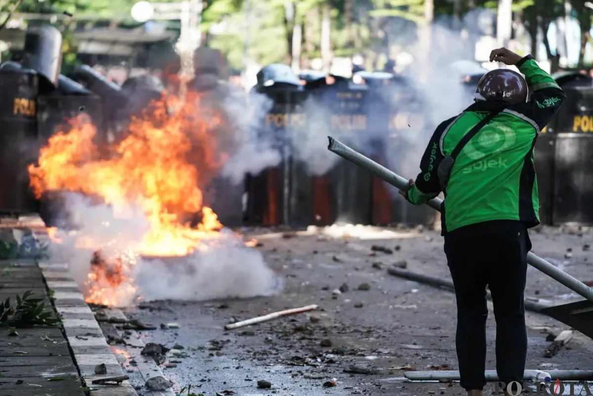 Seorang massa aksi berpakaian ojol menantang pihak keamanan dalam demonstrasi di depan Mako Brimob Polda Metro Jaya, Kwitang, Jakarta Pusat, Jumat, 29. Agustus 2025. (Sumber: Poskota/Bilal Nugraha Ginanjar)