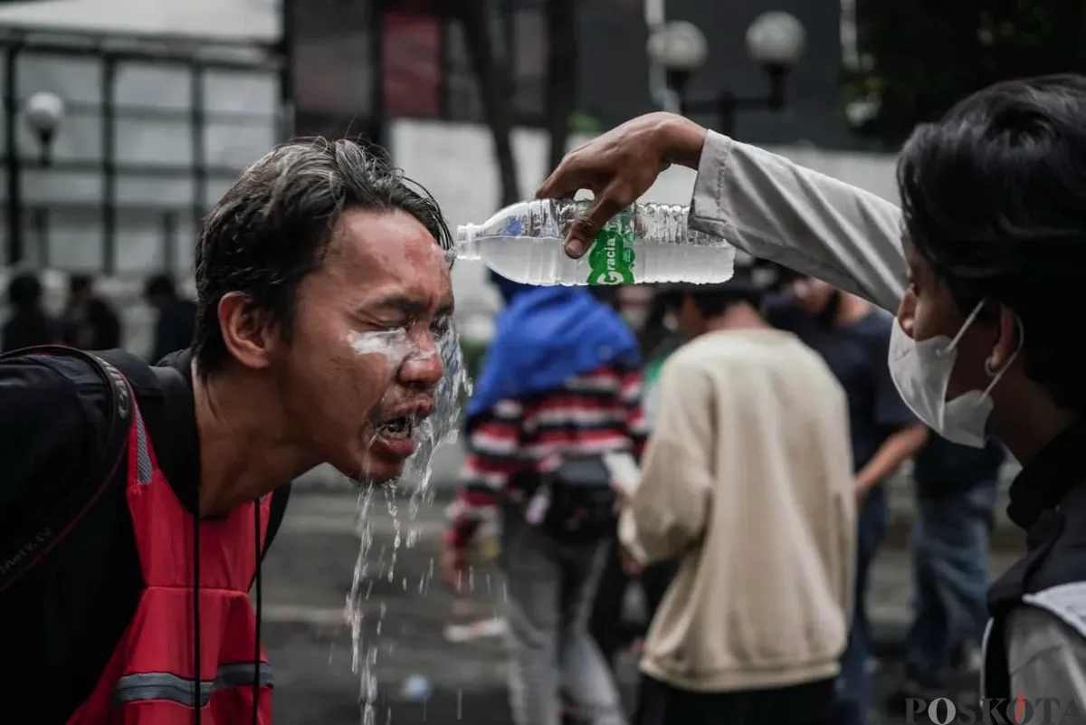 Salah seorang massa aksi disiram air seusai terkena gas saat demonstrasi di Satuan Brimob Polda Metro Jaya, Kecamatan Senen, Jakarta Pusat, Jumat, 29 Agustus 2025. (Sumber: Poskota/Bilal Nugraha Ginanjar)