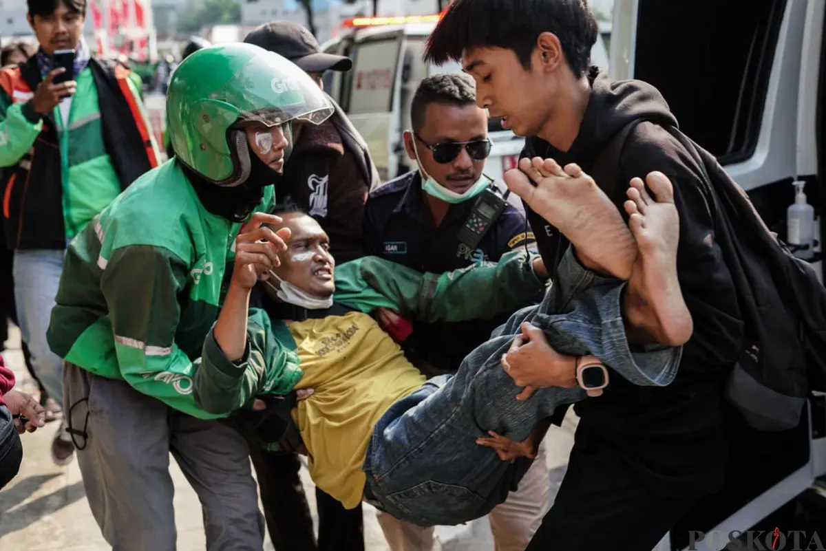 Seorang massa aksi beratribut ojek online (ojol) digotong saat demonstrasi di Satuan Brimob Polda Metro Jaya, Kecamatan Senen, Jakarta Pusat, Jumat, 29 Agustus 2025. (Sumber: Poskota/Bilal Nugraha Ginanjar)