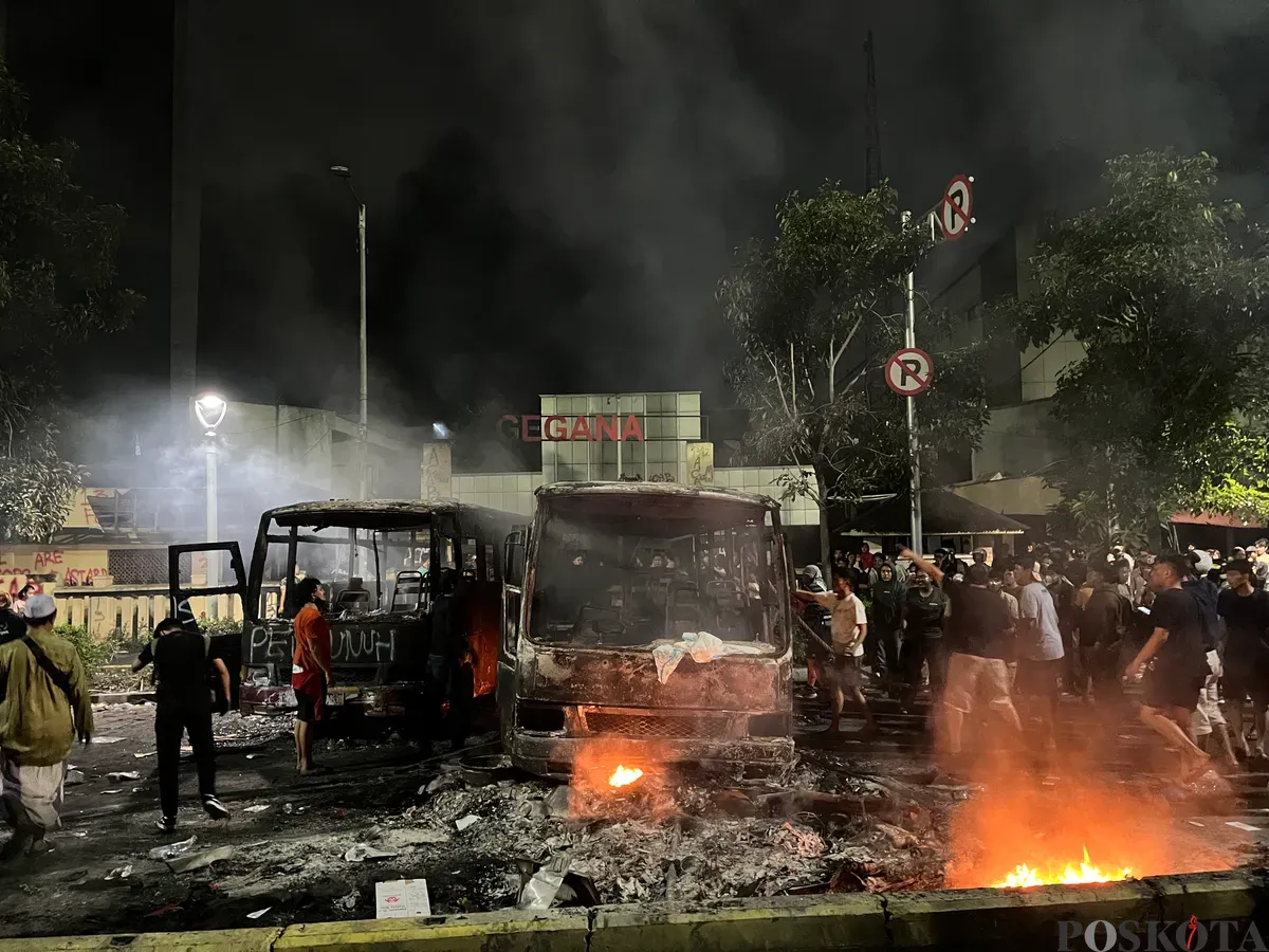 Warga berusaha memindahkan bus yang terbakar agar pemadam kebakaran bisa dapat akses di depan Gedung GEGANA, Jakarta Pusat, Sabtu, 30 Agustus 2025 dini hari. (Sumber: Poskota/Pandi Ramedhan)