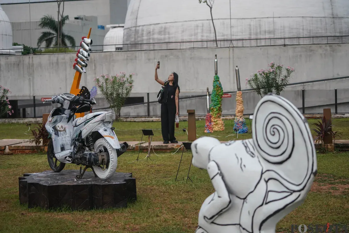 Sejumlah pengunjung melihat karya dalam Pameran Seni Rupa Motorsaikel Kalcer: Gas Aja Dulu yang digelar di Rooftop Garden Plaza Taman Ismail Marzuki (TIM), Jalan Cikini Raya, Menteng, Jakarta, Kamis, 27 November 2025. (Sumber: Poskota/Bilal Nugraha Ginanjar)