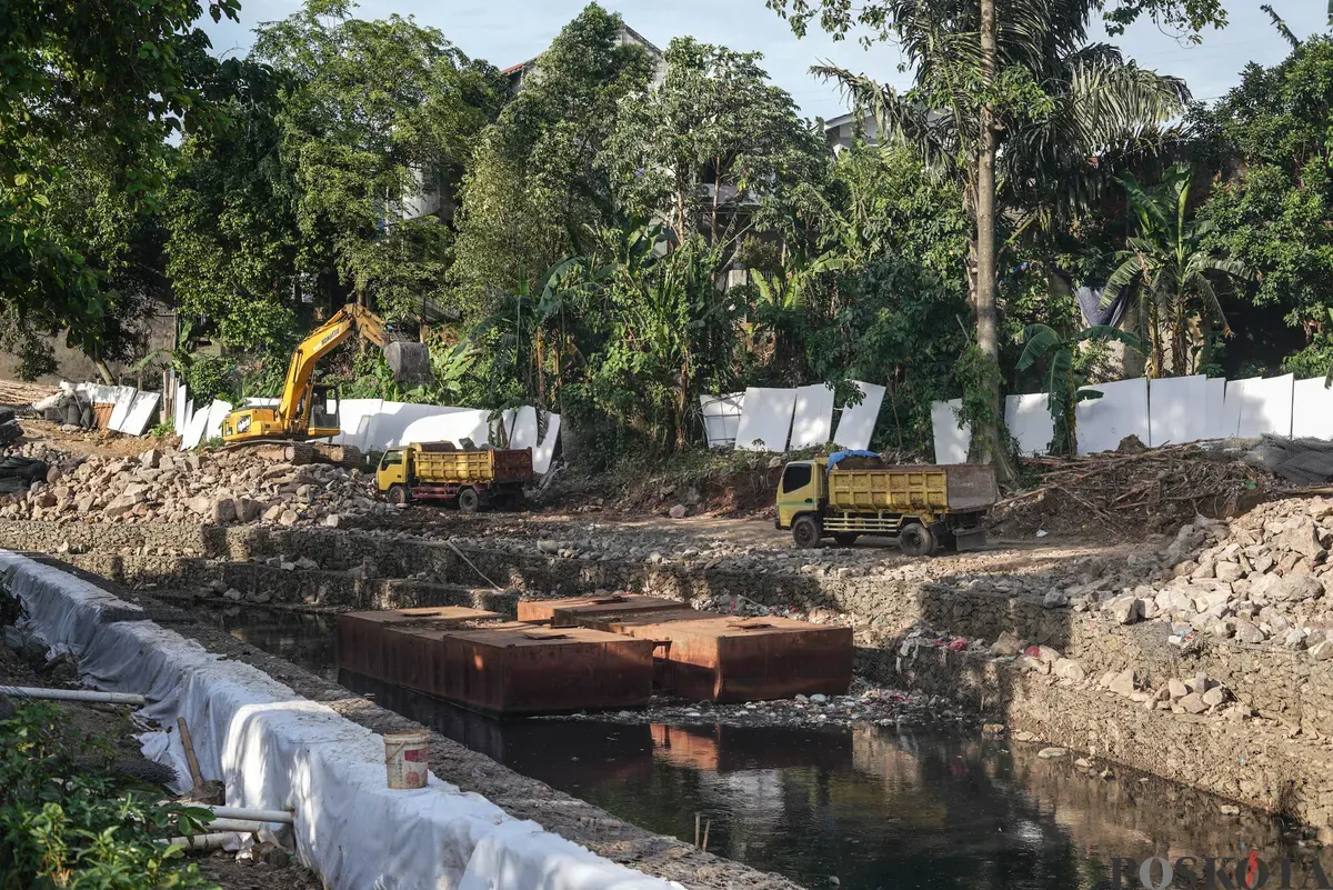 Operator eskavator memindahkan batu kali untuk proyek pembangunan turap bronjong di bantaran Kali Ciliwung, Cililitan, Jakarta, Selasa, 25 November 2025. (Sumber: Poskota/Bilal Nugraha Ginanjar)