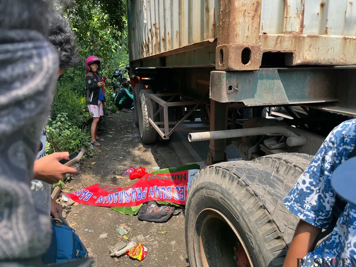 Jenazah siswa SMP yang tewas tertabrak truk petikemas di Jalan Cakung–Cilincing (Cacing), Jakarta Timur, ditutupi spanduk sebelum dievakuasi petugas. (Sumber: Poskota/M. Tegar Jihad)