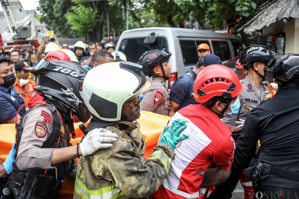 Petugas mengevakuasi jenazah korban kebakaran di perkantoran Terra Drone di Jalan Letjen Soeprapto, Cempaka Baru, Kemayoran, Jakarta Pusat, Selasa, 9 Desember 2025. (Sumber: POSKOTA | Foto: Bilal Nugraha Ginanjar)