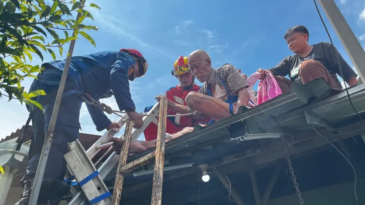 Petugas mengevakuasi lansia terjebak di atap rumah kawasan Citayam, Kecamatan Bojonggede, Kabupaten Bogor. (Sumber: Dok. Damkar Bogor)