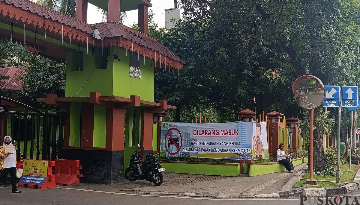 Pemkot Bekasi memasang spanduk sosialisasi larangan masuk kantor bagi kendaraan yang belum membayar pajak di pintu masuk. (Sumber: POSKOTA | Foto: Nurpini Aulia Rapika)