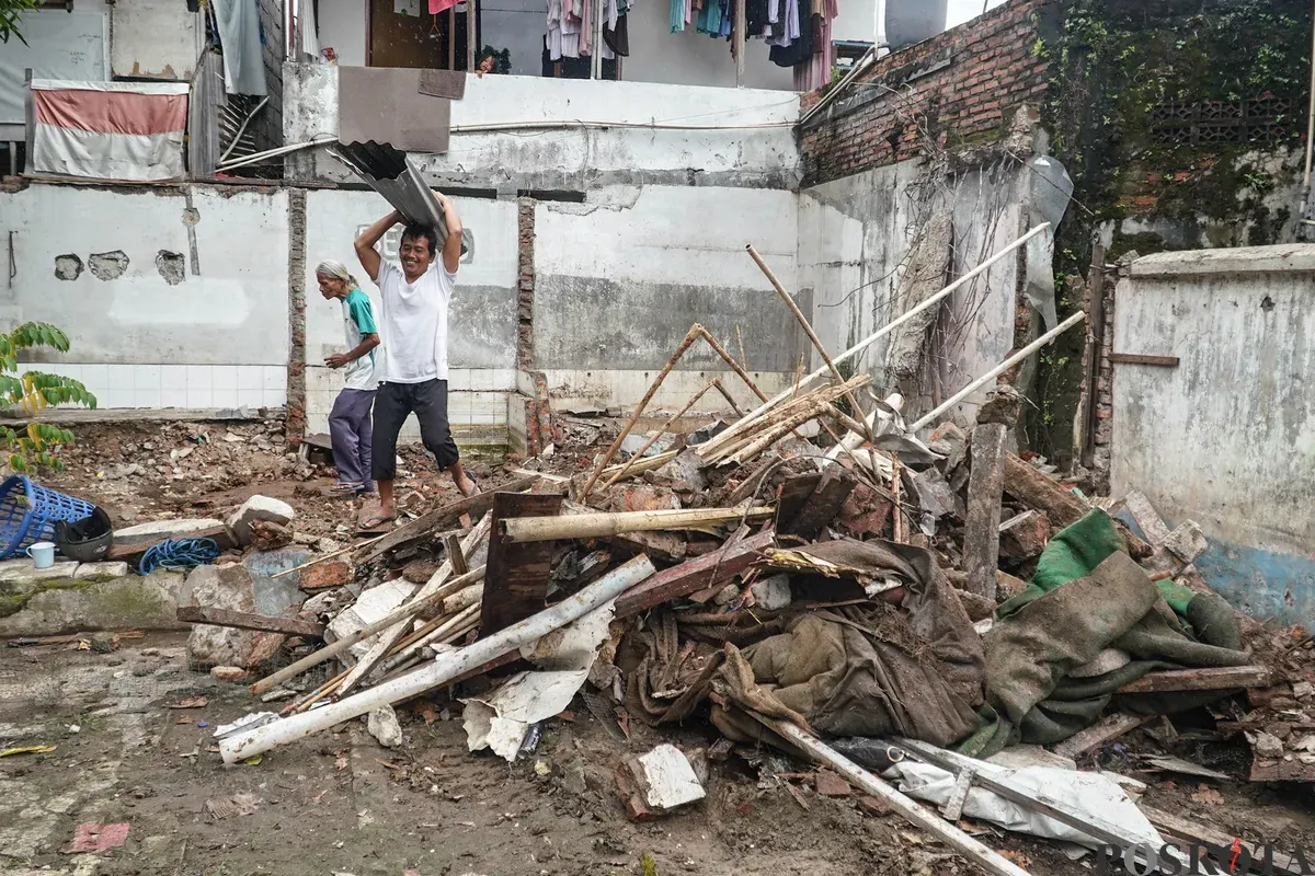 Petugas Penanganan Prasarana dan Sarana Umum (PPSU) membawa barang bongkaran rumah warga di TPU Kober Rawa Bunga, Jatinegara, Jakarta Timur, Kamis, 18 Desember 2025. (Sumber: Poskota/Bilal Nugraha Ginanjar)