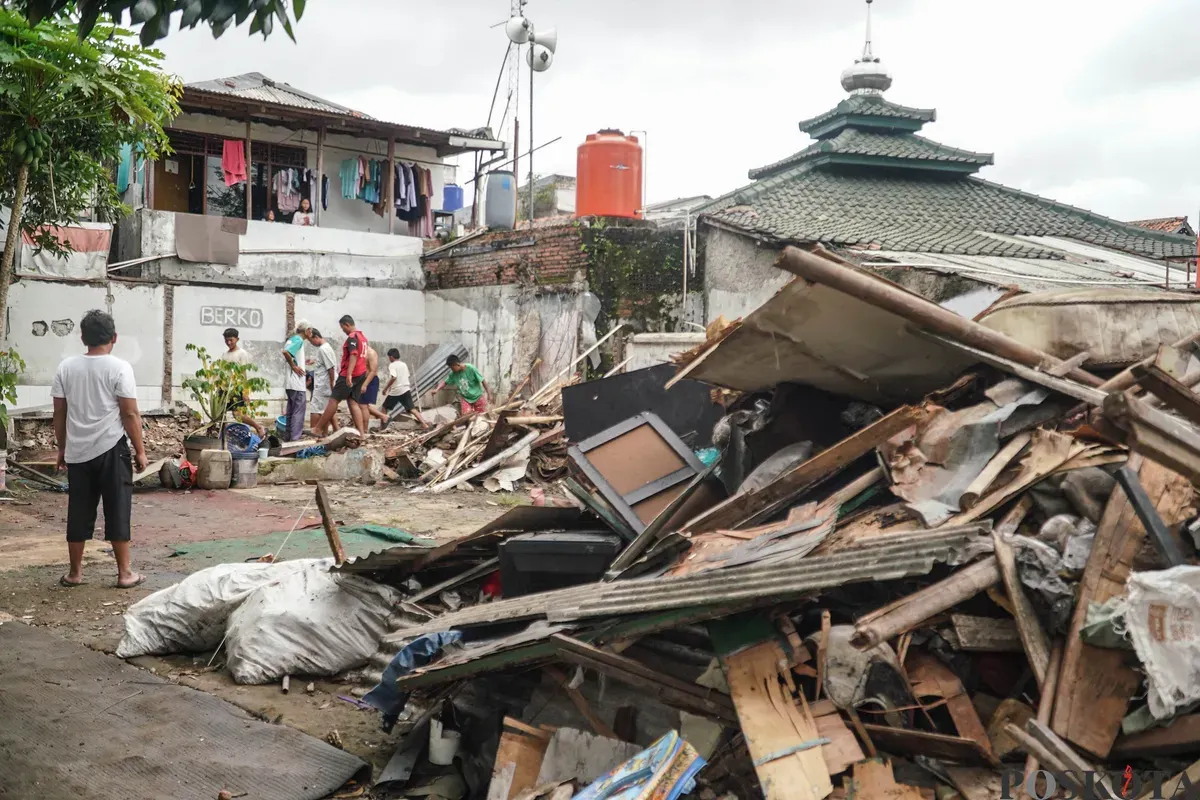 Petugas Penanganan Prasarana dan Sarana Umum (PPSU) membawa barang bongkaran rumah warga di TPU Kober Rawa Bunga, Jatinegara, Jakarta Timur, Kamis, 18 Desember 2025. (Sumber: Poskota/Bilal Nugraha Ginanjar)