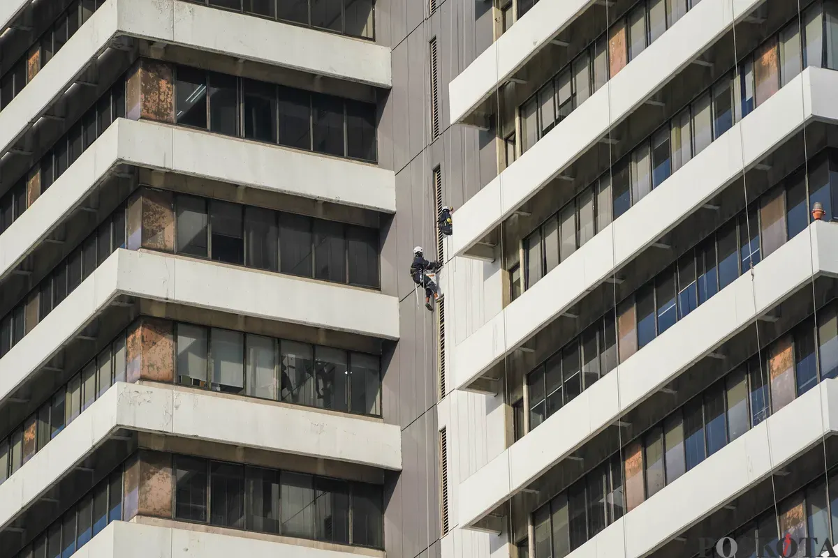 Pekerja membersihkan kaca gedung di Jalan MH Thamrin, Jakarta, Senin, 22 Desember 2025. (Sumber: Poskota/Bilal Nugraha Ginanjar)