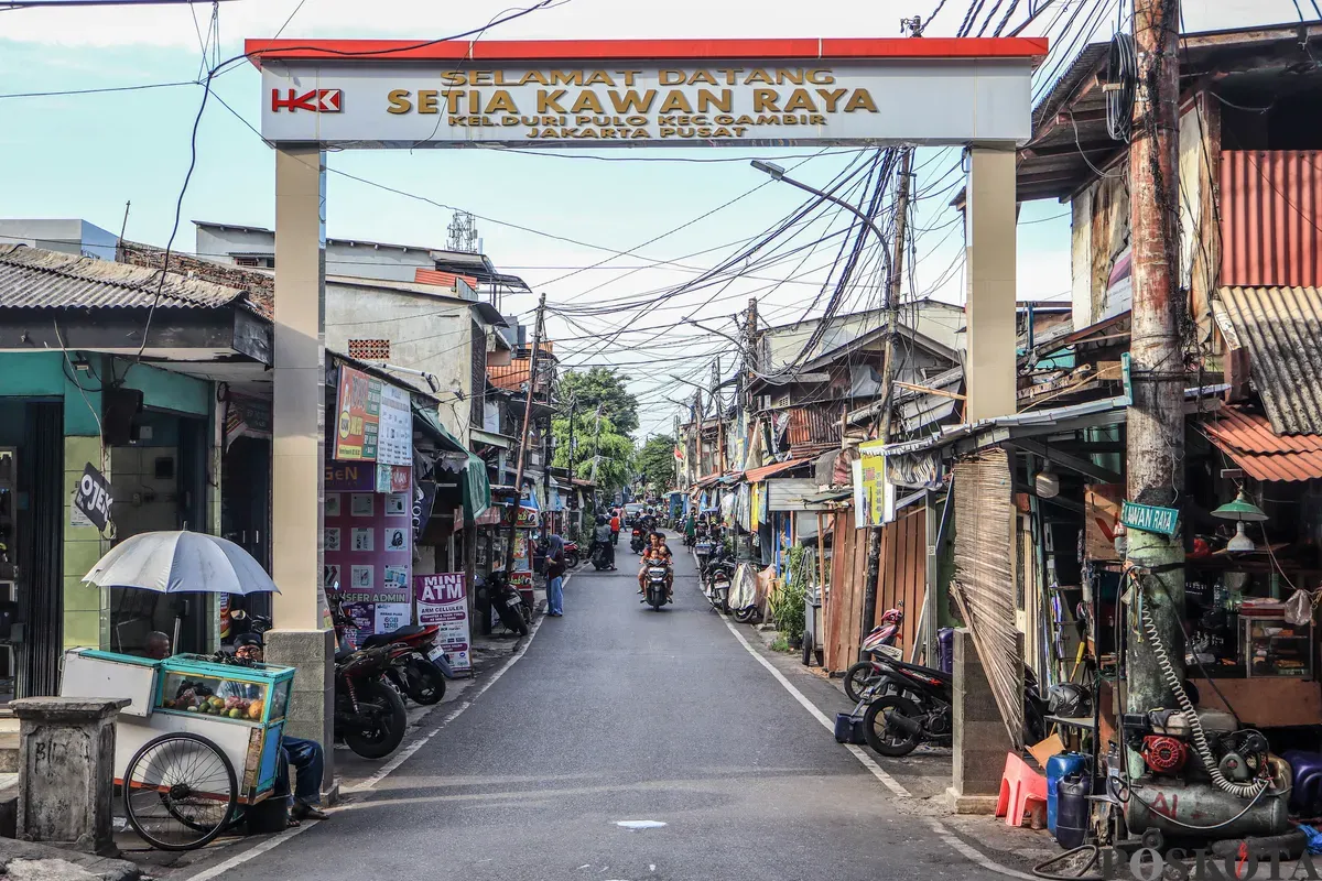 Warga beraktifitas melintasi spanduk penolakan uang ganti rugi tol Semanan Sunter di kawasan RW 09/12, Duri Pulo, Gambir, Jakarta Pusat, Selasa, 23 Desember 2025. (Sumber: Poskota/Dhiya Ahmad Fauzan)