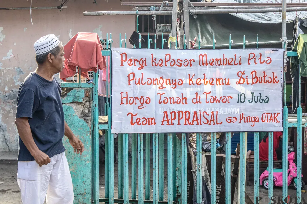 Warga beraktifitas melintasi spanduk penolakan uang ganti rugi tol Semanan Sunter di kawasan RW 09/12, Duri Pulo, Gambir, Jakarta Pusat, Selasa, 23 Desember 2025. (Sumber: Poskota/Dhiya Ahmad Fauzan)