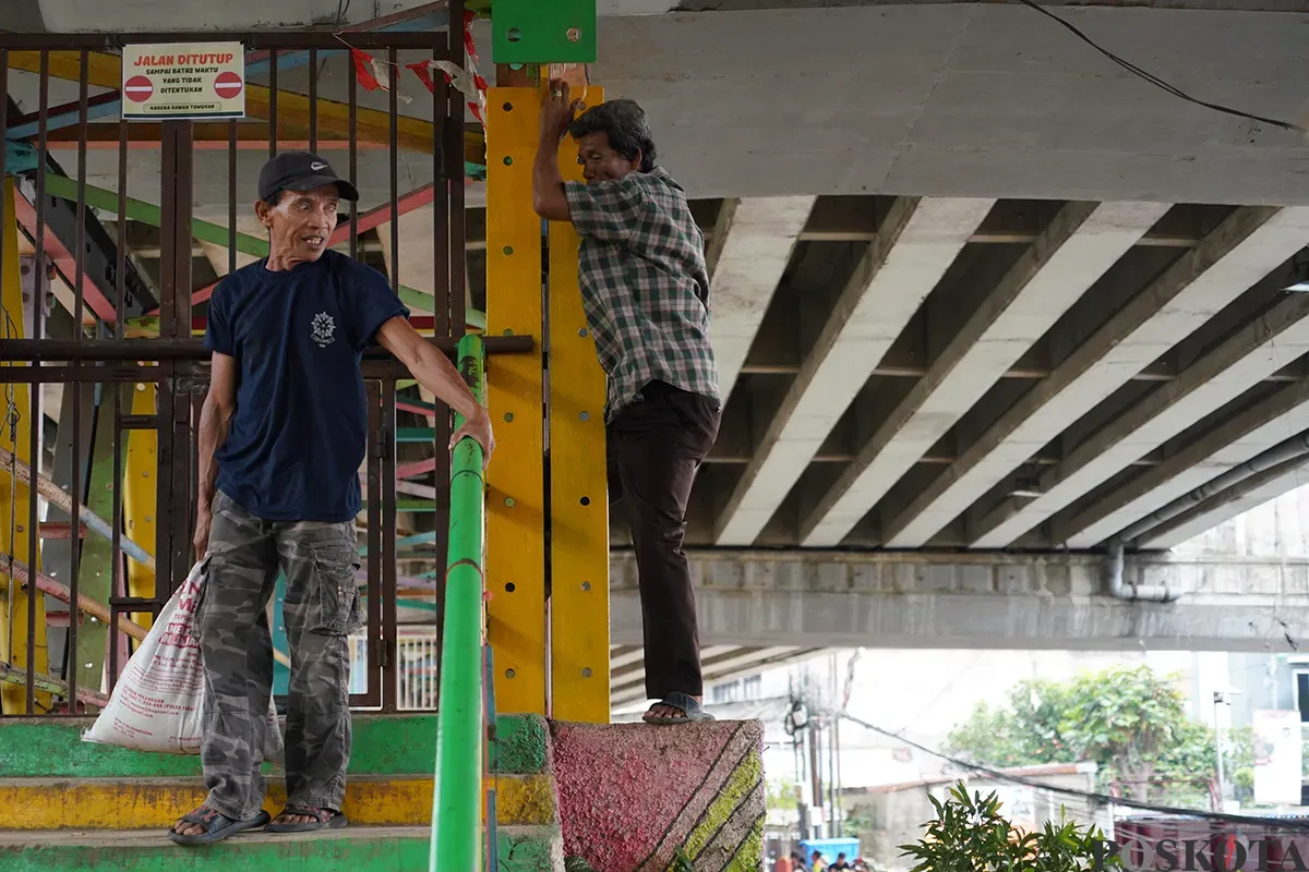 Warga berupaya menerobos pagar besi penutup dengan cara memanjat di Jembatan Penyebrangan Orang (JPO) Kolong Flyover Kalibata, Jakarta Selatan, Selasa, 4 Februari 2025. (Sumber: Poskota/Bilal Nugraha Ginanjar)