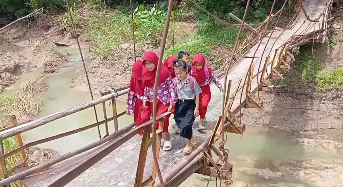 Sejumlah anak-anak SD di Desa Nanggala, Kecamatan Cikeusik, Kabupaten Pandeglang, saat melintas jembatan gantung yang nyaris putus. (Sumber: Dok. Warga)