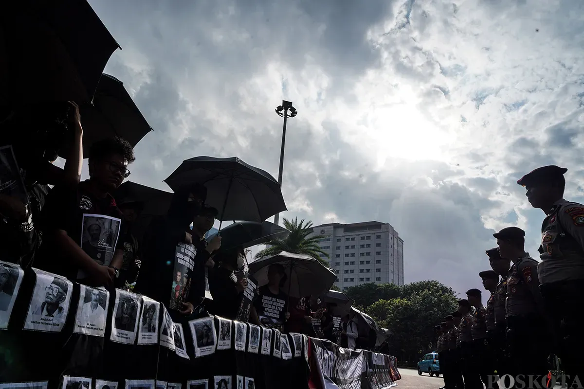 Sejumlah aktivis menggunakan baju hitam sambil membawa payung dan poster kejadian, mengikuti Aksi Kamisan Peringatan 36 Tahun Peristiwa Talangsari Lampung, di depan Istana Merdeka, Jakarta, Kamis, 7 Februari 2025. (Sumber: Poskota/Bilal Nugraha Ginanjar)