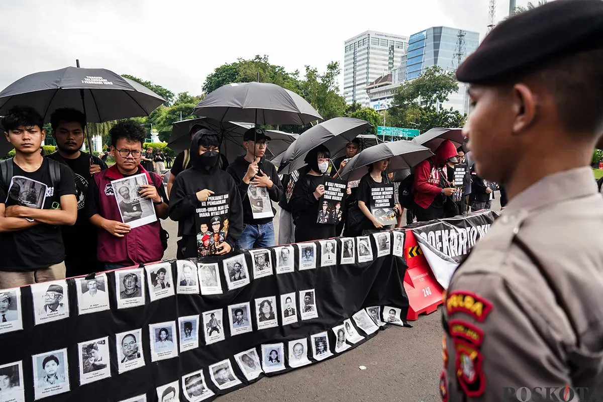 Sejumlah aktivis menggunakan baju hitam sambil membawa payung dan poster kejadian, mengikuti Aksi Kamisan Peringatan 36 Tahun Peristiwa Talangsari Lampung, di depan Istana Merdeka, Jakarta, Kamis, 7 Februari 2025. (Sumber: Poskota/Bilal Nugraha Ginanjar)