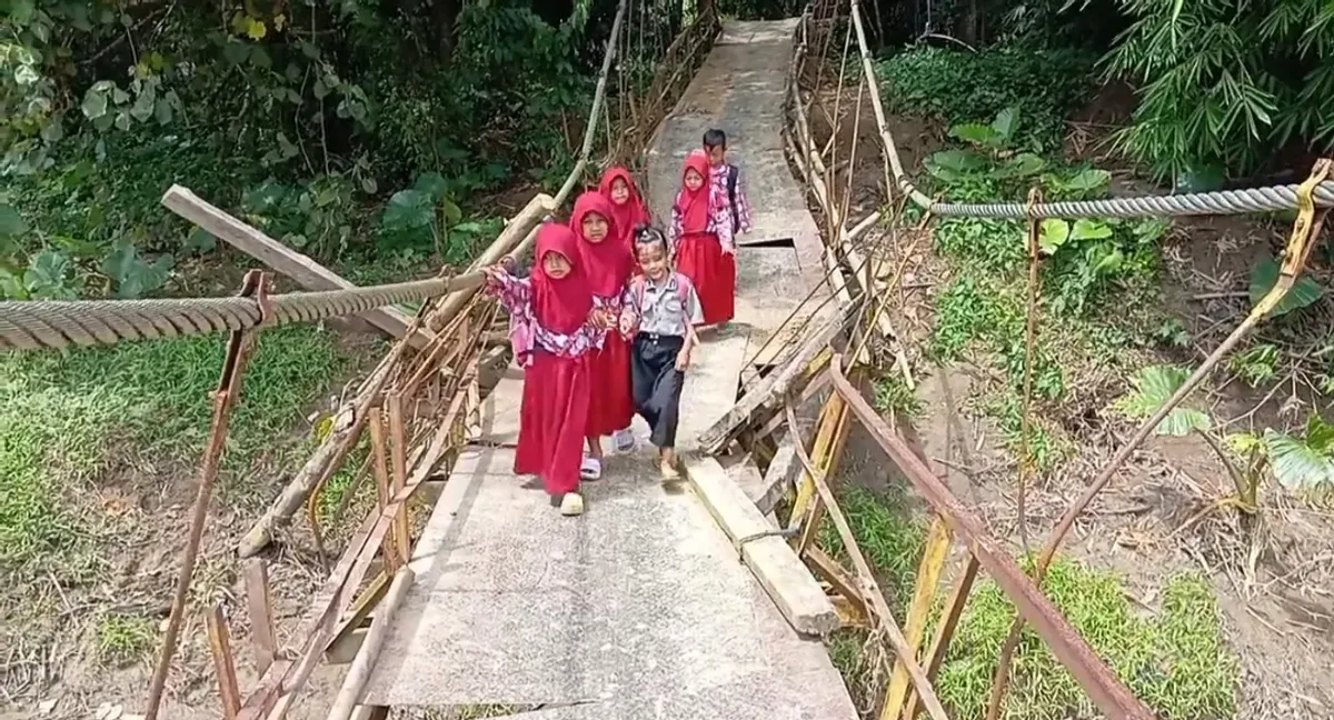 Sejumlah murid SD melintasi jembatan gantung yang nyaris ambruk di Desa Nanggala, Kecamatan Cikeusik, Kabupaten Pandeglang. (Sumber: Dok. Warga)