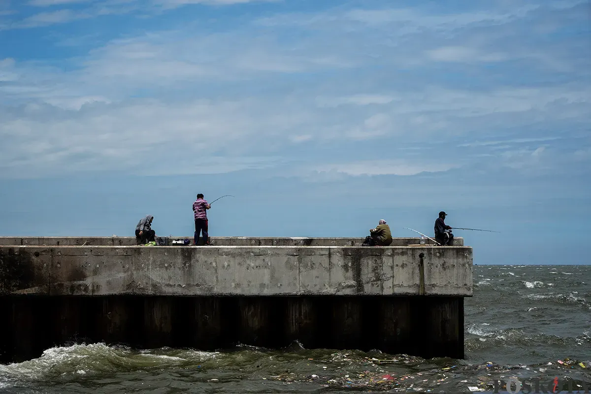 Sejumlah warga memancing ikan laut dari atas tanggul Muara Baru, Penjarjngan, Jakarta Utara, Rabu, 5 Februari 2025. (Sumber: Poskota/Bilal Nugraha Ginanjar)