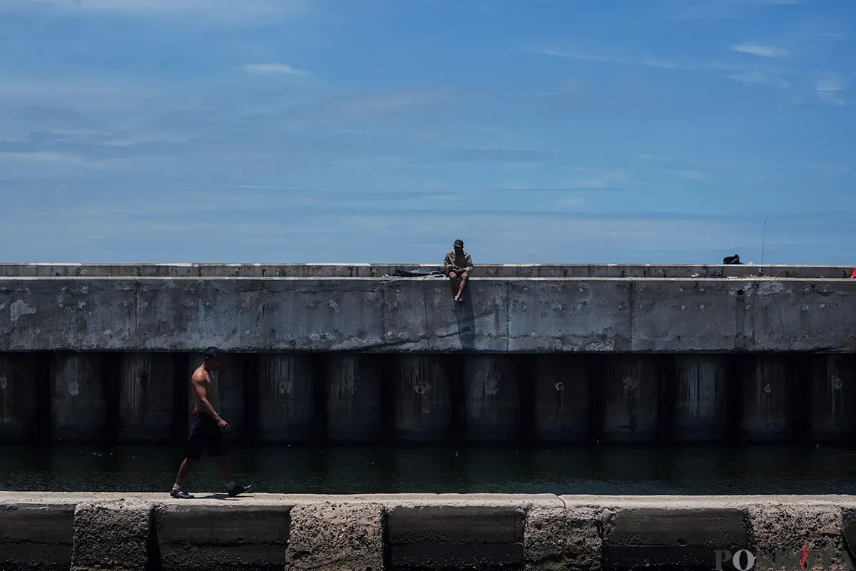 Warga beraktifitas di tanggul laut raksasa Dermaga Muara Baru, Penjaringan, Jakarta Utara, Rabu, 5 Februari 2025. (Sumber: Poskota/Bilal Nugraha Ginanjar)