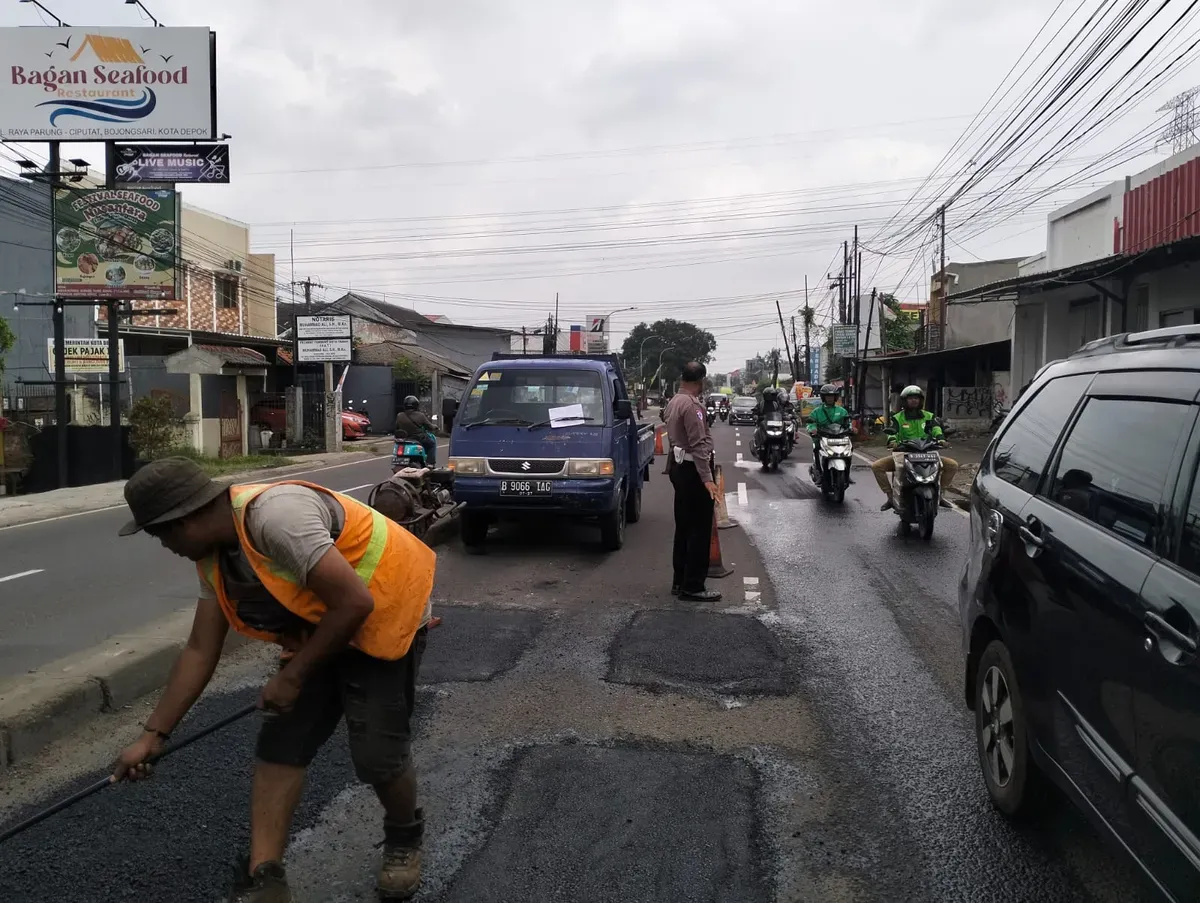 Kanitlantas Polsek Bojongsari, Iptu Suwardi melakukan penjagaan di lokasi penambalan jalan rusak di Jalan Raya Ciputat-Parung, Bojongsari Baru, Bojongsari, Kota Depok. (Sumber: Dok. Satlantas Polsek Bojongsari)