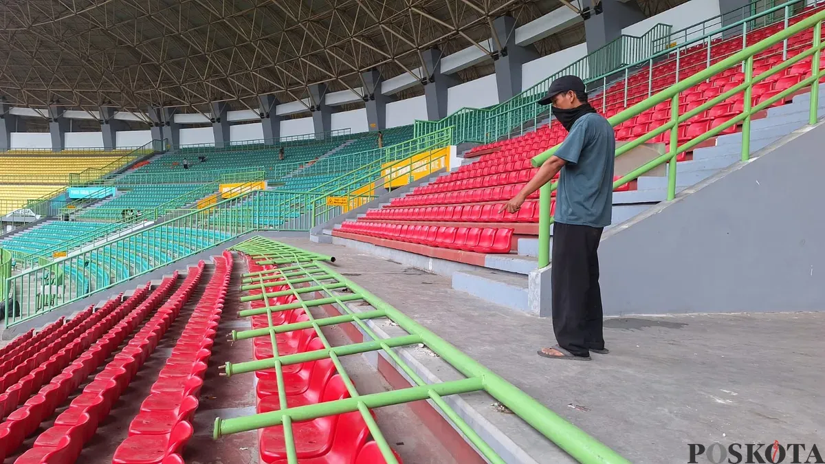 Salah satu pekerja menunjukkan salah satu pagar tribun Stadion Patriot Chandrabaga, mengalami kerusakan, Senin, 17 Februari 2025. (Sumber: Poskota/Ihsan Fahmi)