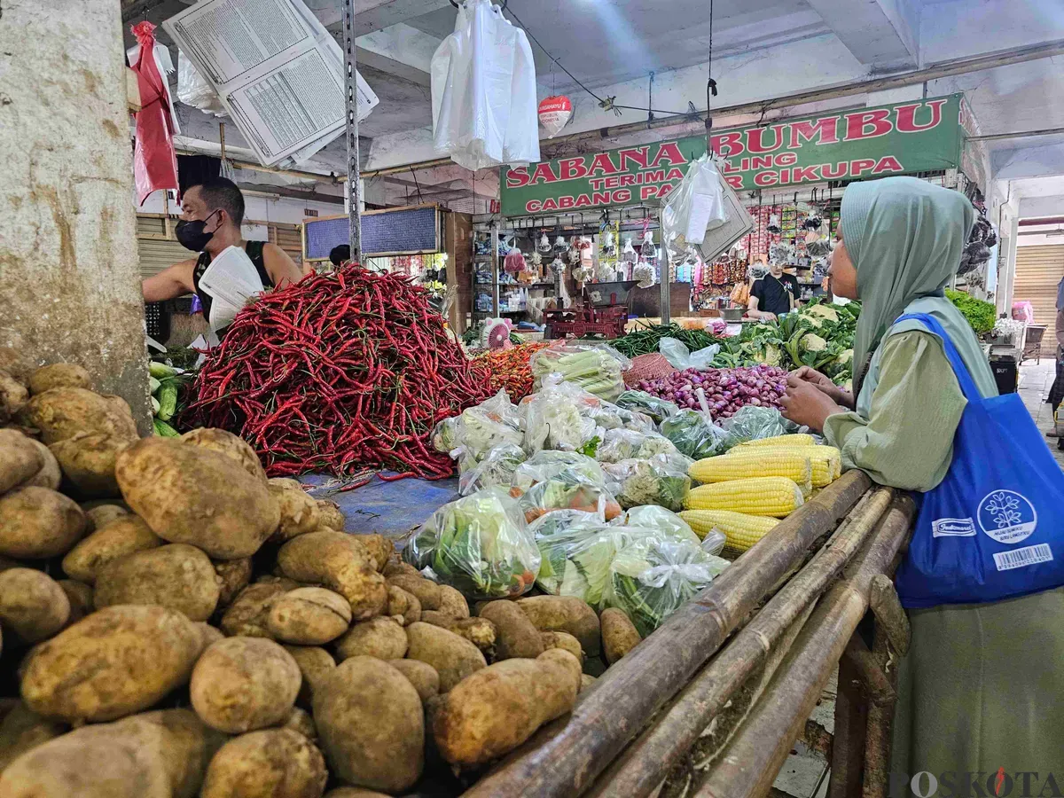 Aliudin, pedagang sayuran di Pasar Gudang Tigaraksa saat sedang melayani konsumen, Selasa, 18 Februari 2025. Harga kentang di pasar ini mengalami kenaikan. (Sumber: Poskota/Veronica Prasetio)