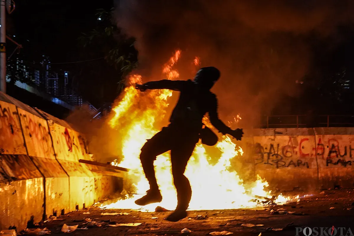 Massa aksi mulai melemparkan benda tumpul seperti batu dan menembakan kembang api ke arah polisi yang berjaga pada aksi unjuk rasa di sekitar Patung Arjuna Wijaya, Jakarta, 21 Februari 2025. (Sumber: Poskota/Bilal Nugraha Ginanjar)