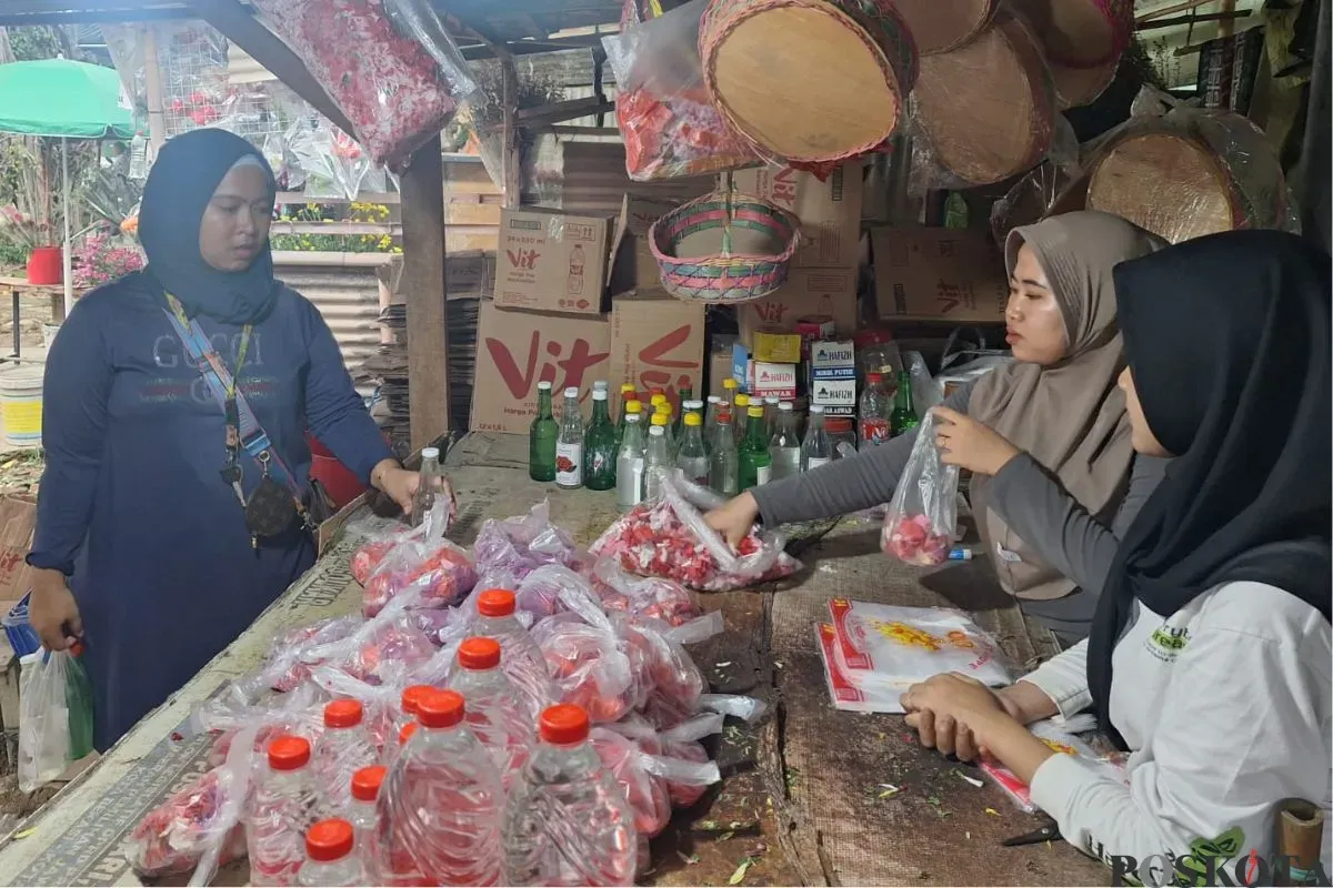 Mila (jilbab cokelat) bersama sepupunya sedang melayani pelanggan yang membeli bunga makam di lapaknya di TPU Perwira, Bekasi Utara, Kota Bekasi, Minggu, 23 Februari 2025. (Sumber: Poskota/Ihsan Fahmi)