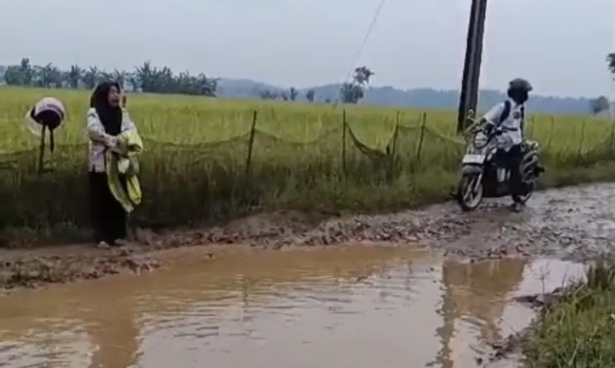 Seorang guru menangis di tepi Jalan Cimoyan, Kecamatan Patia, Pandeglang, yang kondisinya rusak parah. (Sumber: Dok. Warga)