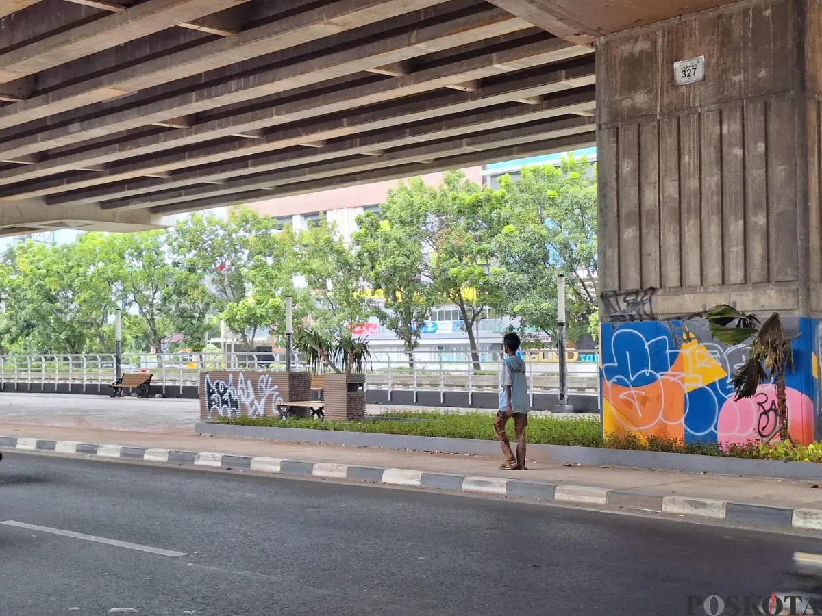 Seorang warga sedang melintas di atas trotoar taman Kalimalang yang tercoreng aksi vandalisme, di Jalan Kh Noer Ali, Bekasi Selatan, Kota Bekasi. Minggu, 5 Januari 2025. (Sumber: Poskota/Ihsan)