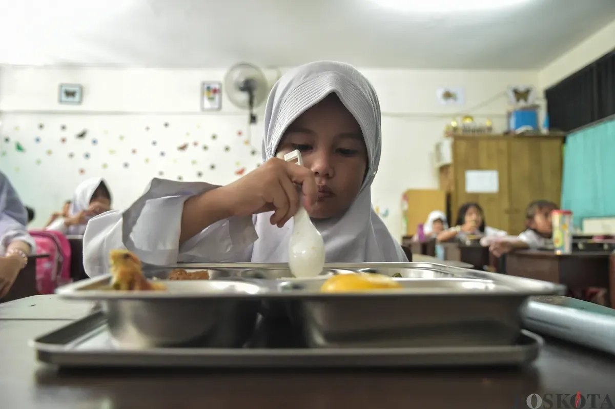 Sejumlah siswa menyantap menu makan siang dari program Makan Bergizi Gratis (MBG) Nasional di ruang kelas SDN Slipi 15, Jakarta Barat, Senin, 6 Januari 2025. (Sumber: Poskoata/ Bilal Nugraha Ginanjar)