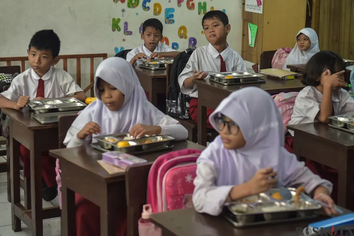 Sejumlah siswa menyantap menu makan siang dari program Makan Bergizi Gratis (MBG) Nasional di ruang kelas SDN Slipi 15, Jakarta Barat, Senin, 6 Januari 2025. (Sumber: Poskoata/ Bilal Nugraha Ginanjar)