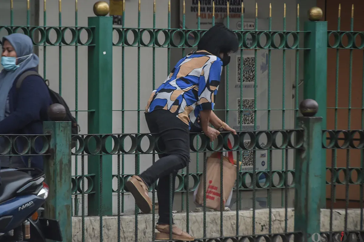 Sejumlah calon penumpang kereta api melompati pagar pembatas jalan raya dengan jalur pejalan kaki di kawasan Stasiun Cikini, Jakarta Pusat, Selasa, 7 Januari 2025.  (Poskota/ Bilal Nugraha Ginanjar) (Sumber: Poskoata/ Bilal Nugraha Ginanjar)