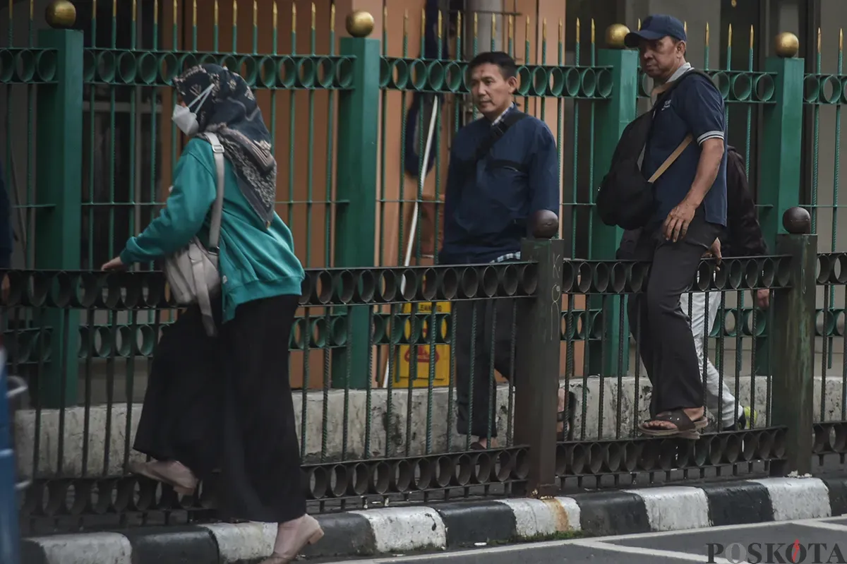 Sejumlah calon penumpang kereta api melompati pagar pembatas jalan raya dengan jalur pejalan kaki di kawasan Stasiun Cikini, Jakarta Pusat, Selasa, 7 Januari 2025.  (Poskota/ Bilal Nugraha Ginanjar) (Sumber: Poskoata/ Bilal Nugraha Ginanjar)