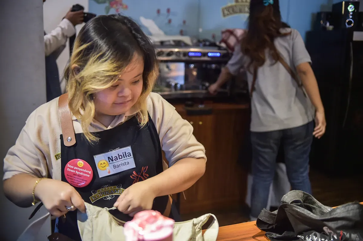 Wanita penyandang down Syndrome sekaligus berprofesi sebagai peracik kopi (Barista) ketika mengisi aktivitasnya mulai dari mempersiapkan, meracik hingga menyajikan minuman kopi pesanan pelanggannya di Kedai Kopi Kamu, Jakarta Selatan, Selasa, 7 Desember 2025. (Poskota/ Bilal Nugraha Ginanjar) (Sumber: Poskoata/ Bilal Nugraha Ginanjar)