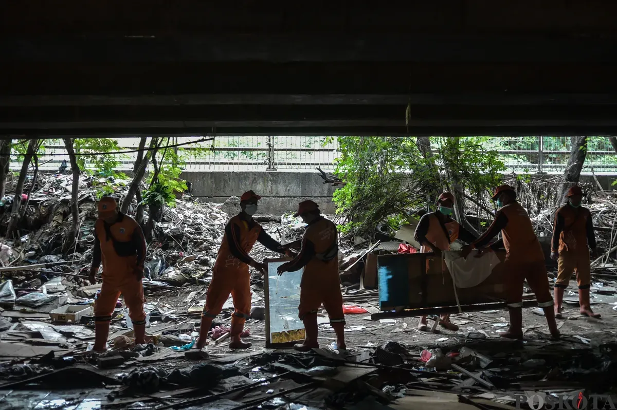 Petugas Suku Dinas Jakarta Barat, membersihkan sisa reruntuhan pemukiman di bawah Kolong Tol Angke, Grogol Petamburan, Jakarta Barat, Selasa, 7 Januari 2025. (Sumber: Poskota/Bilal Nugraha Ginanjar)