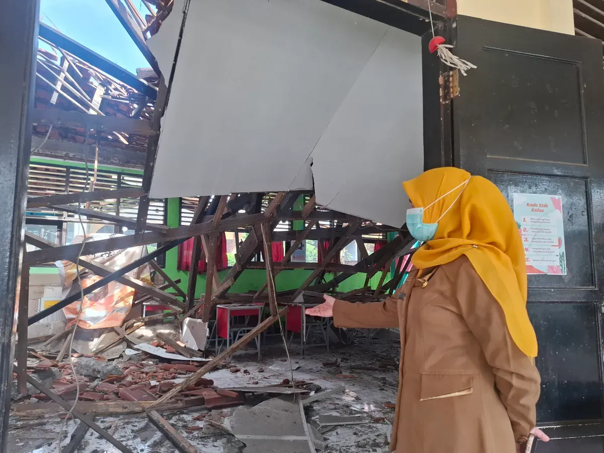 Kepala Sekolah SDN Mekarjaya 29 Kota Depok, Rika Kartini, menunjukkan ambruknya atap ruang kelas di SDN tersebut, karena rangka kayu yang sudah lapuk termakan usia, Senin, 13 Januari 2025. (Sumber: Poskota/Angga)