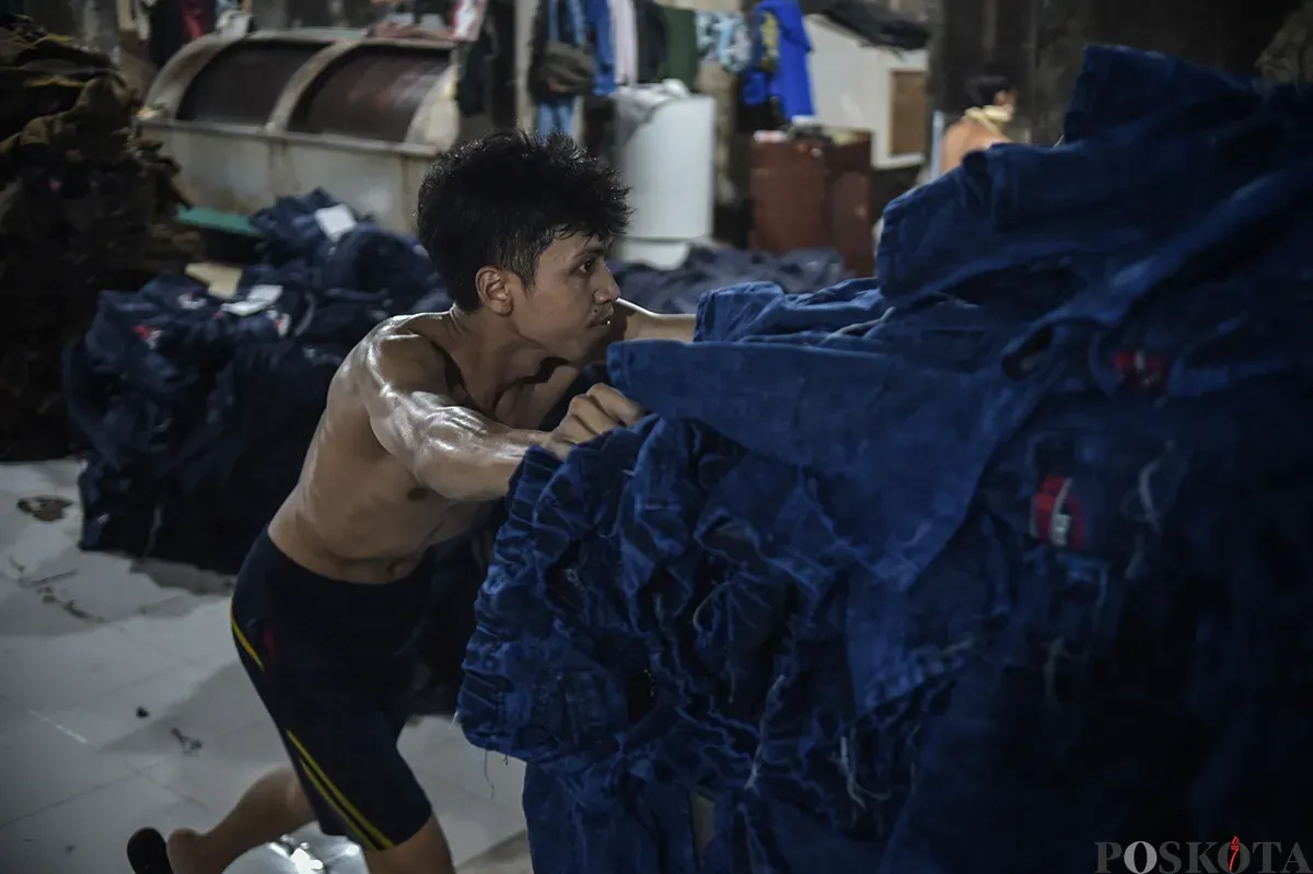 Sejumlah pekerja saat menyelesaikan proses pembuatan celana jeans (jins) yang dibuat dari kain berbahan denim, di sentra pembuatan celana di Kampung Baru, Jakarta Selatan, Rabu, 15 Januari 2025. (Sumber: Poskota/Bilal Nugraha Ginanjar)