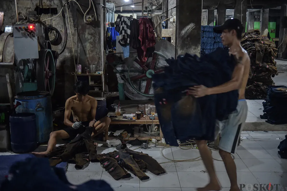 Sejumlah pekerja saat menyelesaikan proses pembuatan celana jeans (jins) yang dibuat dari kain berbahan denim, di sentra pembuatan celana di Kampung Baru, Jakarta Selatan, Rabu, 15 Januari 2025. (Sumber: Poskota/Bilal Nugraha Ginanjar)