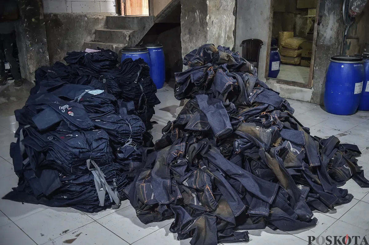 Sejumlah pekerja saat menyelesaikan proses pembuatan celana jeans (jins) yang dibuat dari kain berbahan denim, di sentra pembuatan celana di Kampung Baru, Jakarta Selatan, Rabu, 15 Januari 2025. (Sumber: Poskota/Bilal Nugraha Ginanjar)