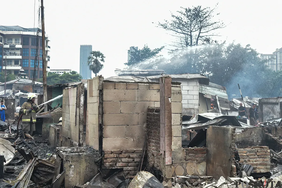 Sejumlah warga menyaksikan proses pendinginan terhadap puing-puing rumah yang terbakar yang dilakukan oleh petugas pemadam kebakaran usai terjadi musibah kebakaran di permukiman padat penduduk di Jalan Kemayoran Gempol, Kemayoran, Jakarta, Selasa, 21 Januari 2025. (Sumber: Poskota/ Bilal Nugraha Ginanjar)