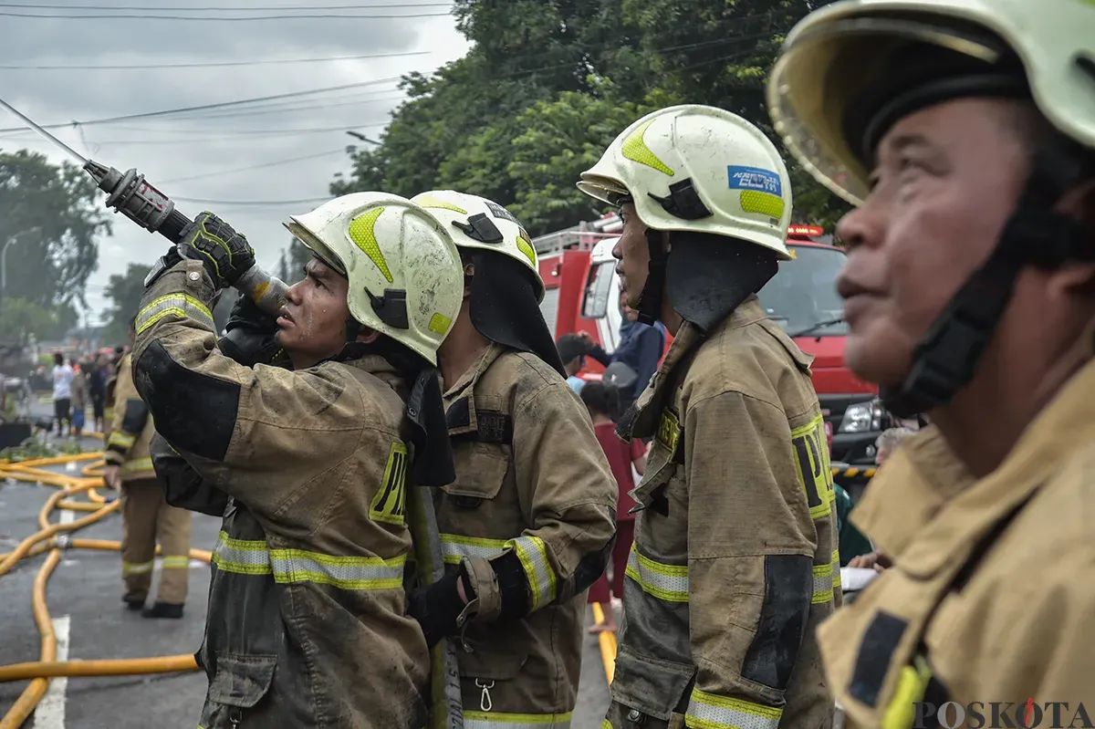 Sejumlah warga menyaksikan proses pendinginan terhadap puing-puing rumah yang terbakar yang dilakukan oleh petugas pemadam kebakaran usai terjadi musibah kebakaran di permukiman padat penduduk di Jalan Kemayoran Gempol, Kemayoran, Jakarta, Selasa, 21 Januari 2025. (Sumber: Poskota/ Bilal Nugraha Ginanjar)