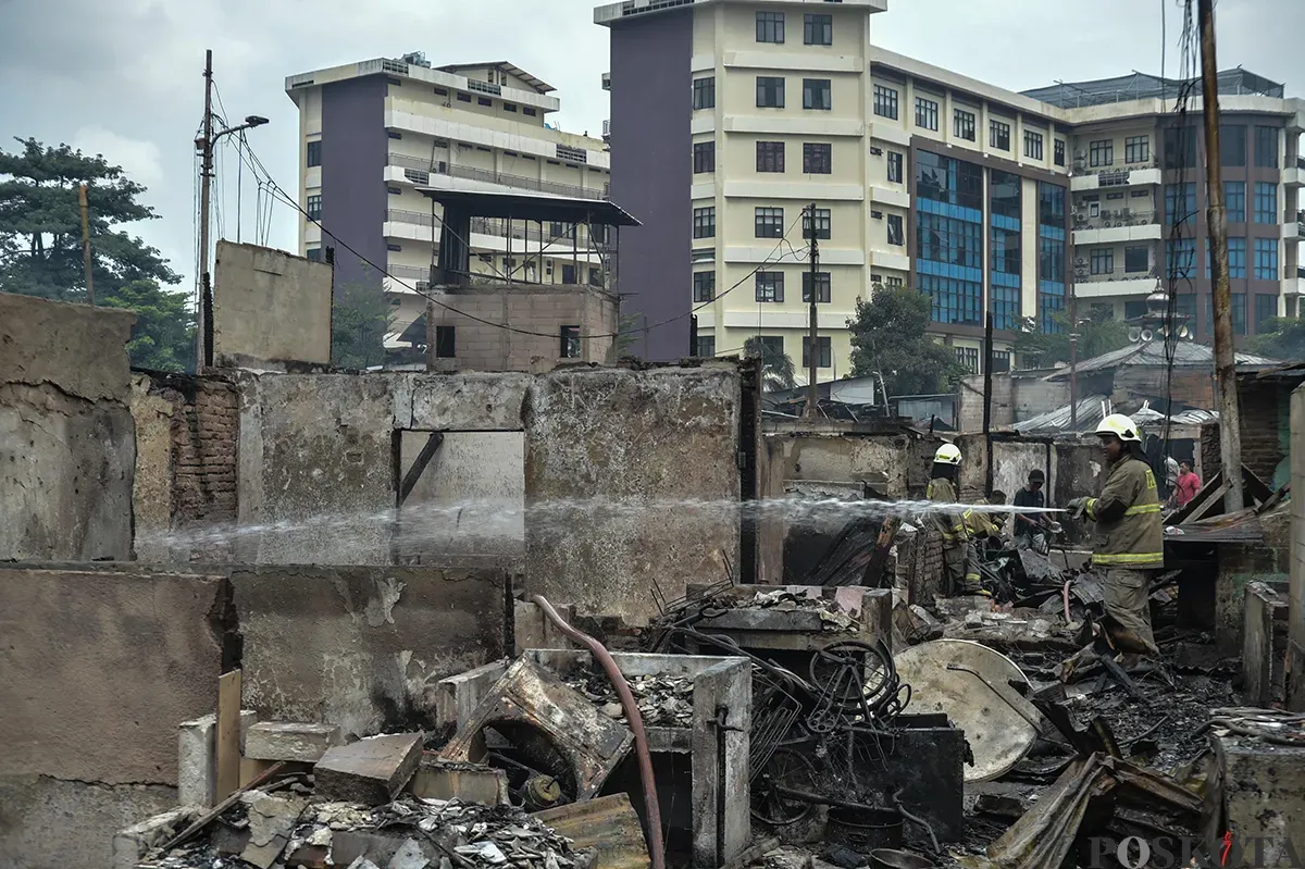 Sejumlah warga menyaksikan proses pendinginan terhadap puing-puing rumah yang terbakar yang dilakukan oleh petugas pemadam kebakaran usai terjadi musibah kebakaran di permukiman padat penduduk di Jalan Kemayoran Gempol, Kemayoran, Jakarta, Selasa, 21 Januari 2025. (Sumber: Poskota/ Bilal Nugraha Ginanjar)