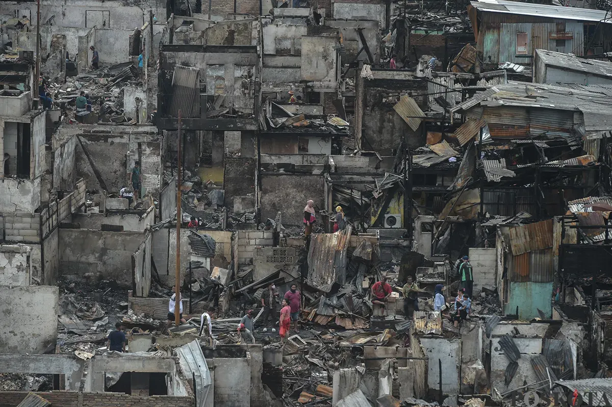 Sejumlah warga menyaksikan proses pendinginan terhadap puing-puing rumah yang terbakar yang dilakukan oleh petugas pemadam kebakaran usai terjadi musibah kebakaran di permukiman padat penduduk di Jalan Kemayoran Gempol, Kemayoran, Jakarta, Selasa, 21 Januari 2025. (Sumber: Poskota/ Bilal Nugraha Ginanjar)
