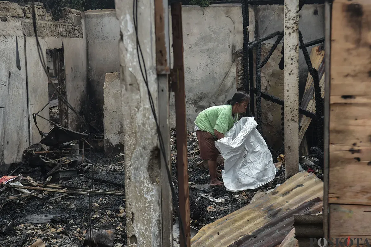 Sejumlah warga menyaksikan proses pendinginan terhadap puing-puing rumah yang terbakar yang dilakukan oleh petugas pemadam kebakaran usai terjadi musibah kebakaran di permukiman padat penduduk di Jalan Kemayoran Gempol, Kemayoran, Jakarta, Selasa, 21 Januari 2025. (Sumber: Poskota/ Bilal Nugraha Ginanjar)