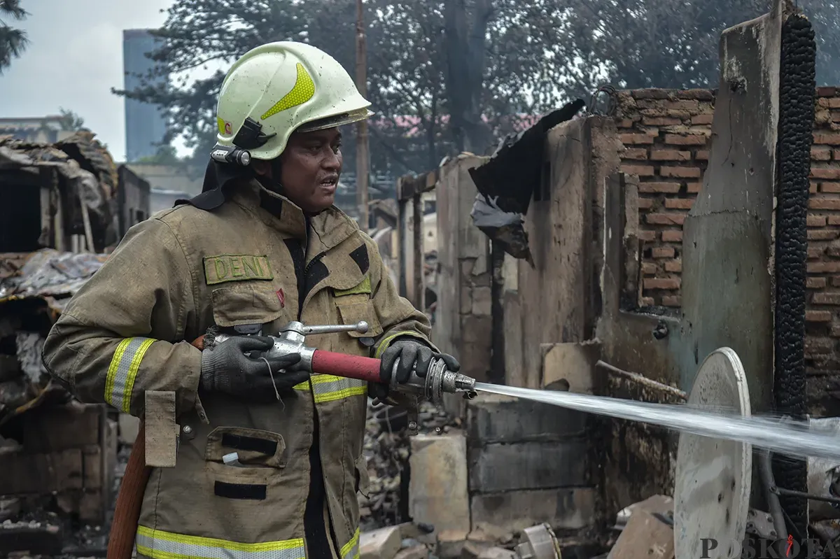 Sejumlah warga menyaksikan proses pendinginan terhadap puing-puing rumah yang terbakar yang dilakukan oleh petugas pemadam kebakaran usai terjadi musibah kebakaran di permukiman padat penduduk di Jalan Kemayoran Gempol, Kemayoran, Jakarta, Selasa, 21 Januari 2025. (Sumber: Poskota/ Bilal Nugraha Ginanjar)