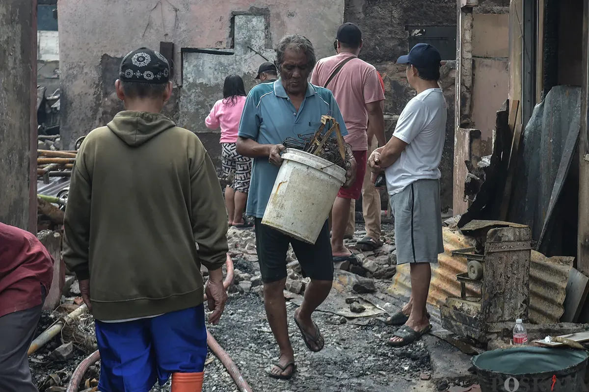 Sejumlah warga menyaksikan proses pendinginan terhadap puing-puing rumah yang terbakar yang dilakukan oleh petugas pemadam kebakaran usai terjadi musibah kebakaran di permukiman padat penduduk di Jalan Kemayoran Gempol, Kemayoran, Jakarta, Selasa, 21 Januari 2025. (Sumber: Poskota/ Bilal Nugraha Ginanjar)