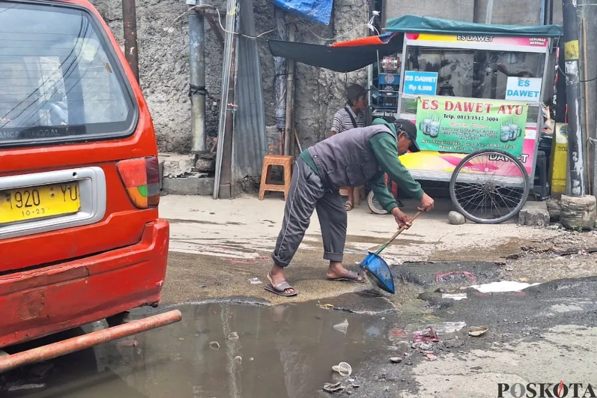 Warga membersihkan genangan air di area Stasiun Bekasi menuju Kampung Pintu, Jalan Raya Perjuangan, Bekasi Utara, Kota Bekasi, Rabu, 22 Januari 2025. (Sumber: Poskota/Ihsan Fahmi)