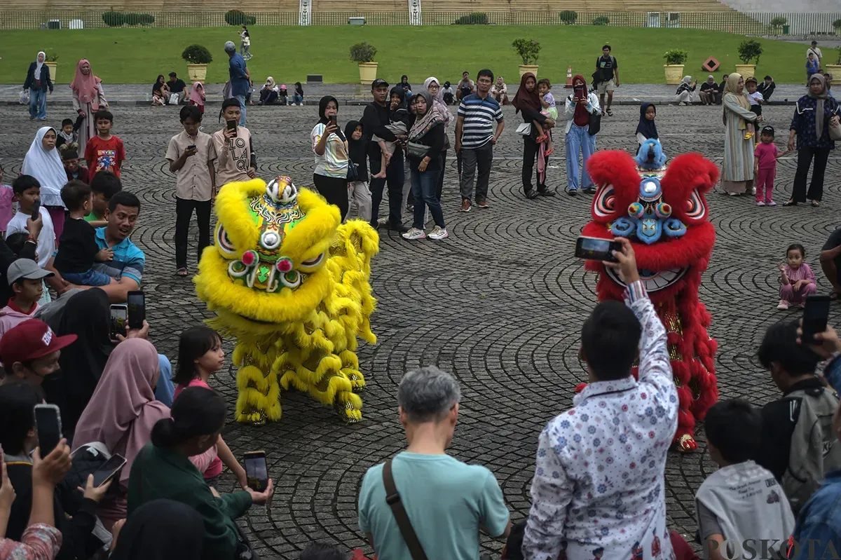 Pengunjung menyaksikan atraksi barongsai yang berlangsung di sisi utara Monumen Nasional (Monas), Jakarta, Selasa, 28 Januari 2025. (Sumber: Poskota/Bilal Nugraha Ginanjar)